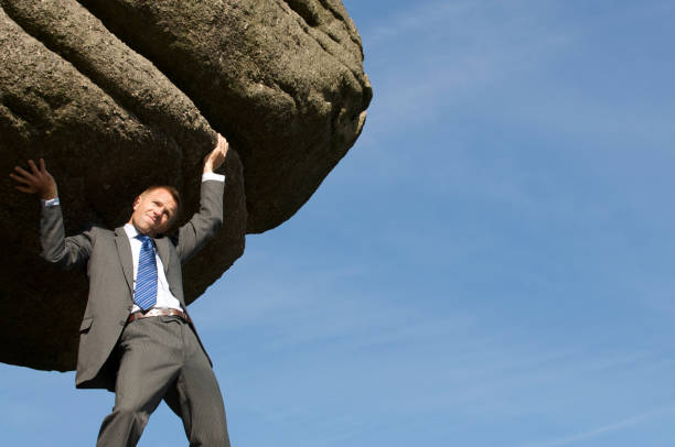 istock Struggling Strong Businessman Holding Huge Rock Boulder into the Sky 157502829