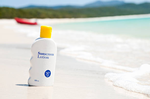 Sunscreen lotion on the beach A bottle of sunscreen lotion on an idyllic tropical beach. suntan lotion photos stock pictures, royalty-free photos & images