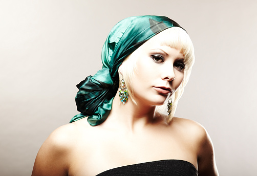 A serious-looking young woman with a head scarf is posing for the camera.  Horizontally framed shot.