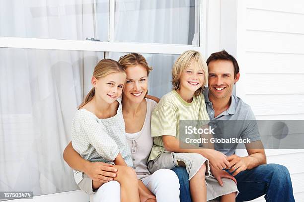 Familie Sitzen Zusammen Vor Haus Stockfoto und mehr Bilder von 8-9 Jahre - 8-9 Jahre, Beide Elternteile, Blick in die Kamera