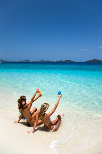 bikini women on spring break making a toast on a tropical beach in the Caribbean