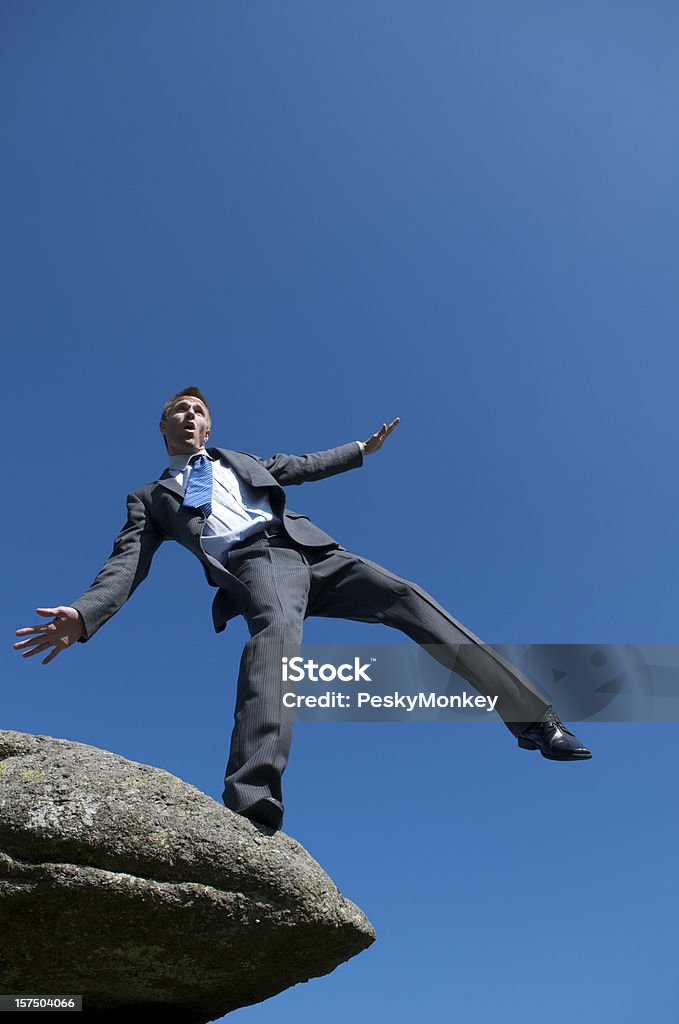 Uomo d'affari di bilanciamento sul bordo della scogliera all'aperto - Foto stock royalty-free di Affari