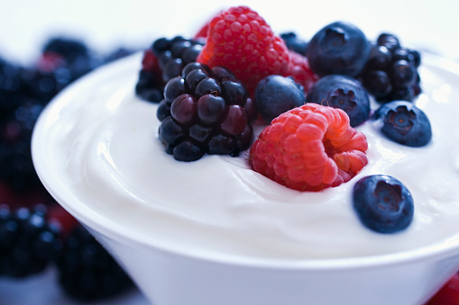 Yogurt with Blueberries, Blackberries, Raspberries. Selective focus,on a white background.
