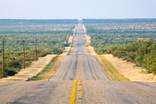 Rural highway heads straight off into the distance, showing compression technique from use of long lens.  Located beween Colorado City, Texas, and Robert Lee, Texas, in Mitchell County, Texas, USA.