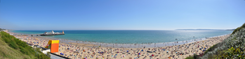 A wide panorama of Bournemouth bay, beach, pier.
