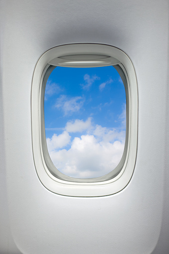 Airplane window with a view of sky and clouds. With clipping path around the inside of the window.