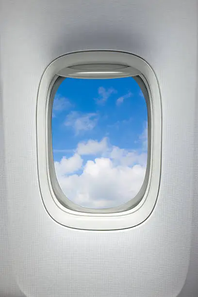 Airplane window with a view of sky and clouds. With clipping path around the inside of the window.