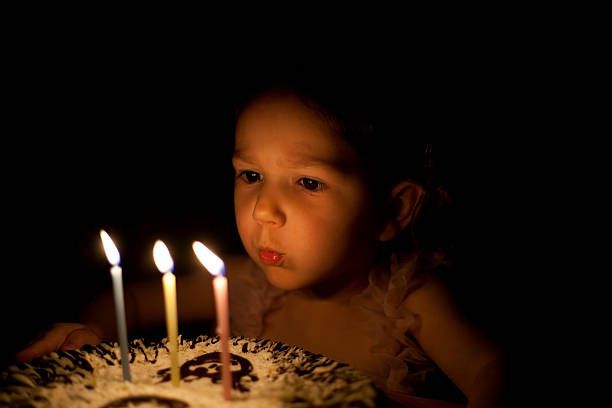 Lovely little girl is making a wish on her third birthday
