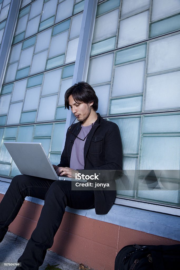 Beau jeune homme sur un ordinateur portable contre le mur - Photo de 20-24 ans libre de droits