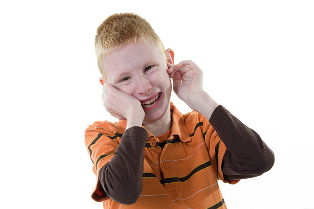 Sad child covering his ears with hands during parents quarrel.