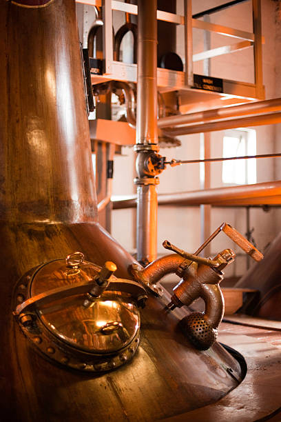 Machines operating a whiskey distillery in Islay, Scotland  Stills in an old whiskey distillery, Islay, Scotland. Original Victorian machinery from1881 is still in use today. distillery still photos stock pictures, royalty-free photos & images