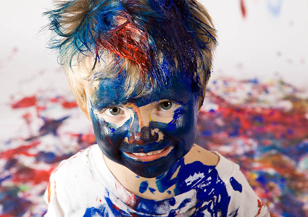 Boy Covered with Paint This is the result of a massive tempera painting free-for-all. child behaving badly stock pictures, royalty-free photos & images