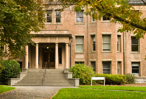A brick building with a green lawn at the University of Washington in Seattle, WA.