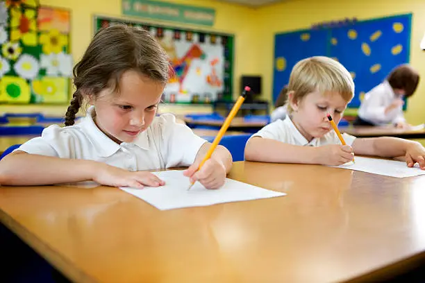 A pair of cute 5 year-old primary school children working hard on their studies in the classroom.