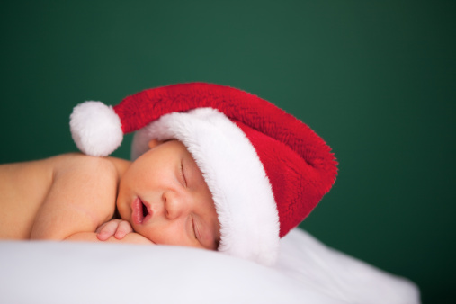 Color photo of a newborn baby wearing a Santa hat for Christmas.