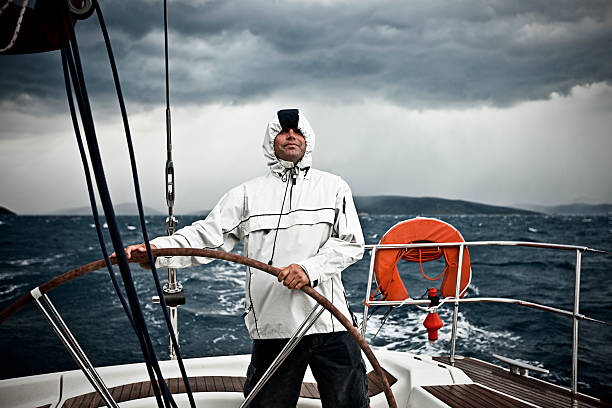 Happy skipper driving sailboat in stormy weather. Heavy rain behind skipper. http://santoriniphoto.com/Template-Sailing.jpg