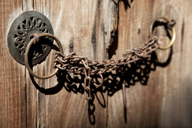 A thick forged iron chain used to lift the fortress bridge against the backdrop of a powerful fortress wall made of natural stone as an architectural background, a fragment of a gate, details and elements of architecture, stock photo, summer.