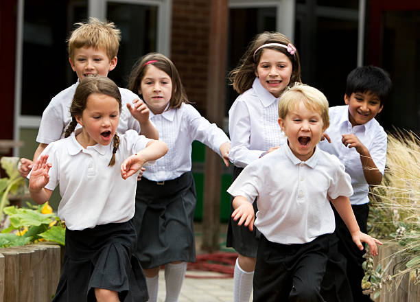 primary school: delighted and excited junior school children leaving class stock photo
