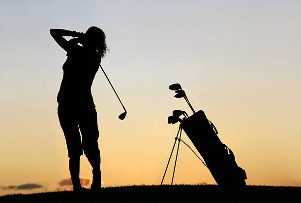 Silhouette of Slim Caucasian Woman Golfing A silhouette of a slim and fit Caucasian woman making a golf swing. Attractive and healthy woman is in her 30s and is demonstrating great balance and excellent form. Golf equipment and golf carry bag is beside her. Unrecognizable woman. Additional themes include golf travel, walking, exercise, sports, fitness, balance, leisure, girls golf trips, golf league, and golf competition.  cropped pants photos stock pictures, royalty-free photos & images