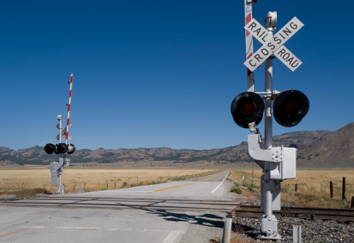 Red light of the railway crossing and lowered barrier blocking the passage