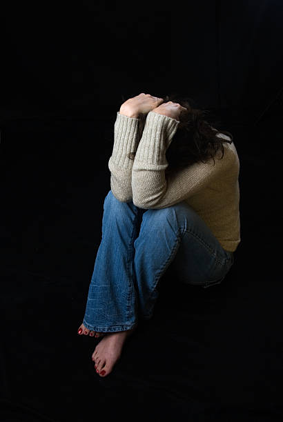Sad woman sitting down covering her face  hugging knees stock pictures, royalty-free photos & images