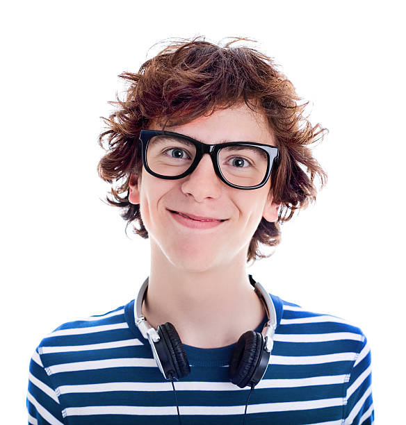 Nerdy Teenager Smiling, Studio Portrait Portrait of a late teen boy wearing black thick rimmed glasses, smiling at camera. Headphones around his neck.  nerd teenager stock pictures, royalty-free photos & images