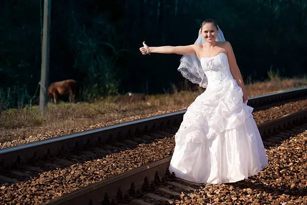 Young woman in white dress pick up a train.