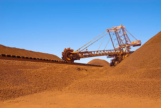 Reclaimer working on an iron ore site under blue sky large reclaimer at a bulk loading facility in Western Australia Reclaimer stock pictures, royalty-free photos & images