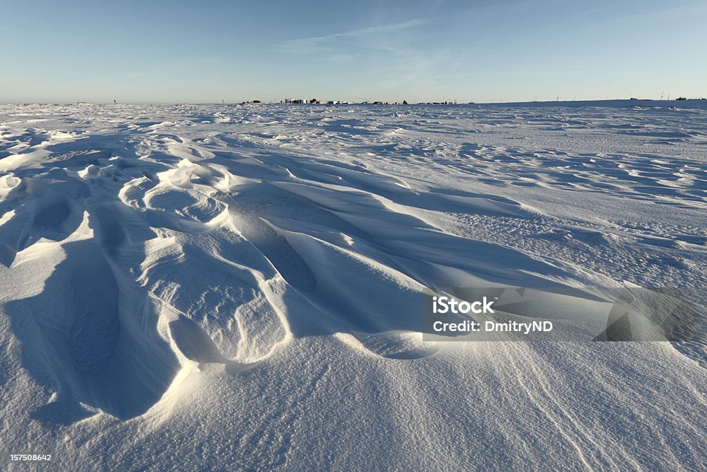 Weathered snowdrift. Oil tanks in horizon . Arctic,  Kolguev Island, Barents Sea, Russia. Arctic Stock Photo