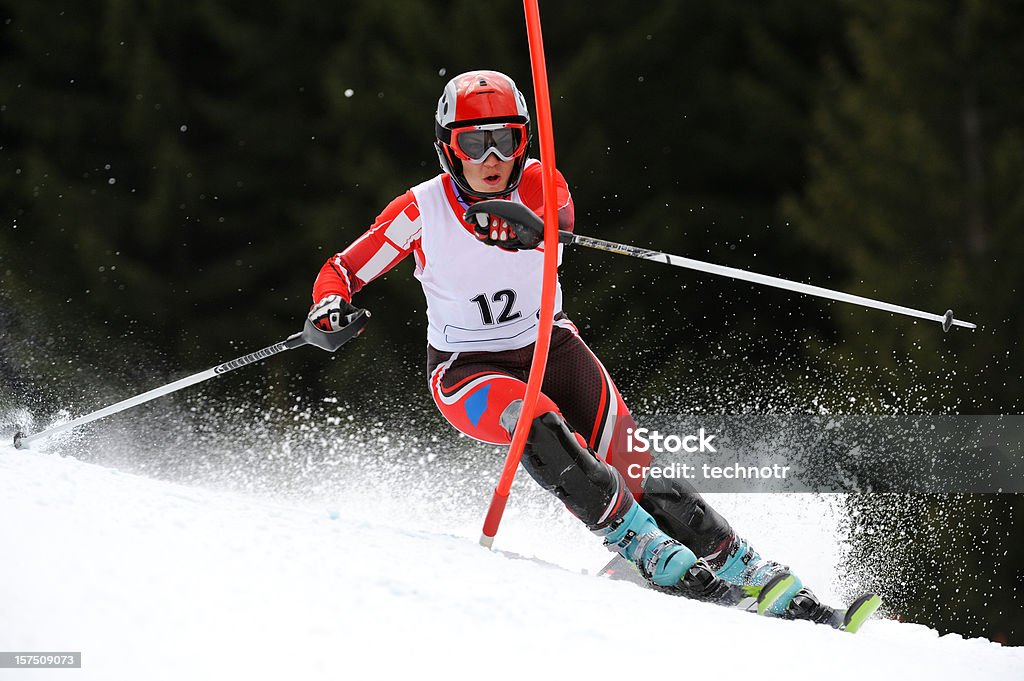 Young women at slalom ski race Front view of young female skier arriving to the red gate during slalom ski race Skiing Stock Photo