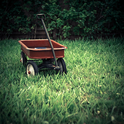 retro red toy wagon in the grass, square composition