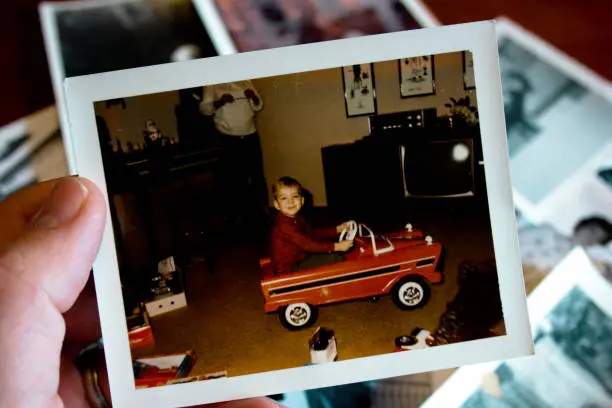 Photo of Hand holds Vintage photograph of boy in pedal car