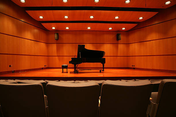 Piano sitting in the middle of the stage in an auditorium Grand Piano on Stage stage light photos stock pictures, royalty-free photos & images