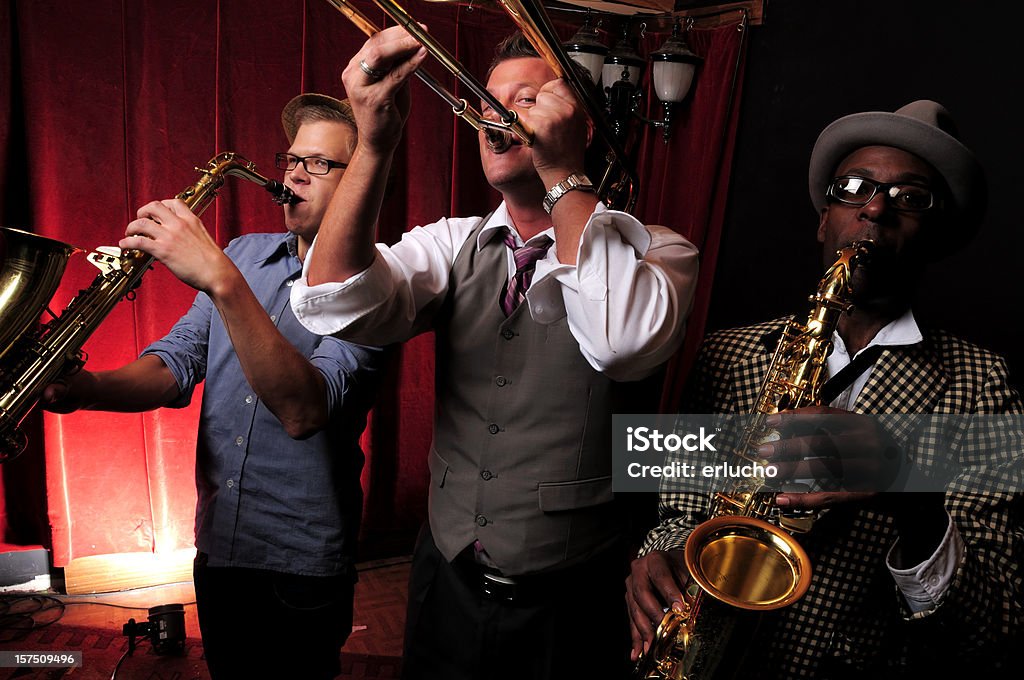 Three jazz musicians playing music with red curtain in back Musicians playing Jazz Bar - Drink Establishment Stock Photo