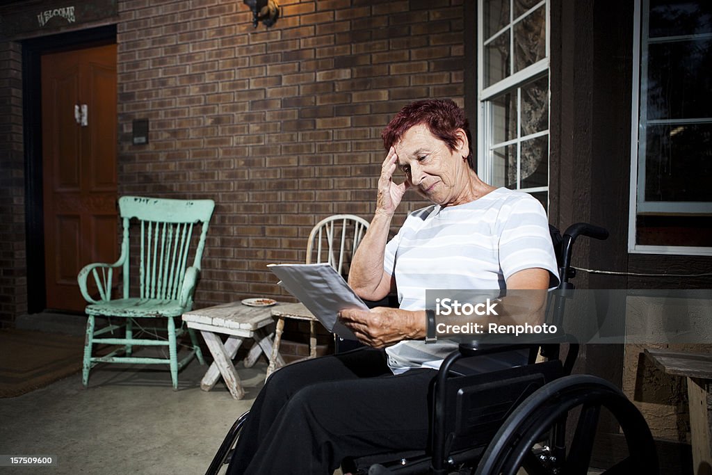 Senior woman in wheelchair worried about paying bills Senior woman in wheelchair worried about paying bills. Physical Disability Stock Photo