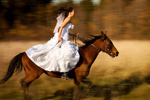 The bride in white dress riding on horse with motion blur on background