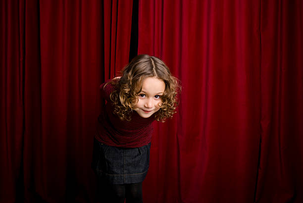 Child actress on a stage theater saluting to the audiencie.