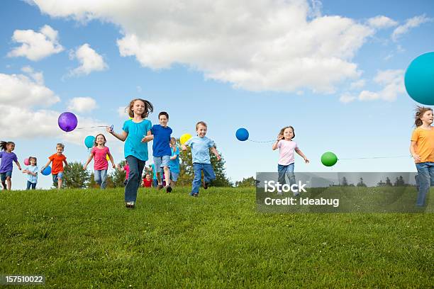 Gruppo Di Bambini Felici In Esecuzione Con Palloncini - Fotografie stock e altre immagini di Bambino