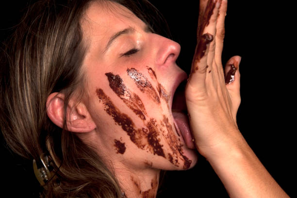 Over Eating, Chocolate Joy Female enjoy licking dirty hands and fingers of chocolate. Portrait of beautiful girl dirty in melted chocolate. chocolate fingers stock pictures, royalty-free photos & images