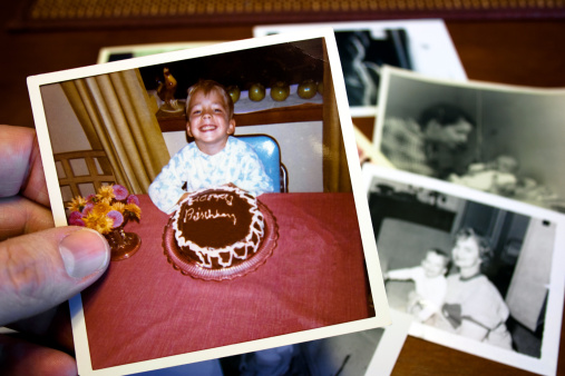 Hand holds Vintage photograph of child and birthday cake