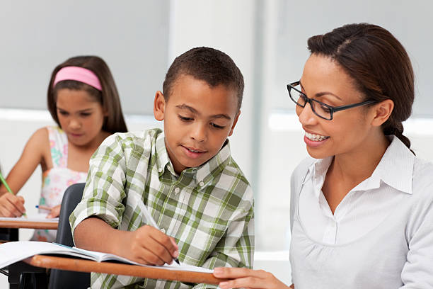 istock Smiling teacher helping school boy with studies 157510879