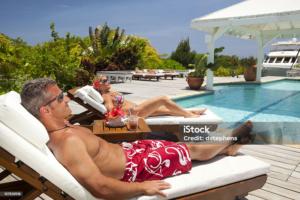 Älteres Paar Genießen Sie einen entspannenden Urlaub am Pool in Luxusresort - Lizenzfrei Männer Stock-Foto