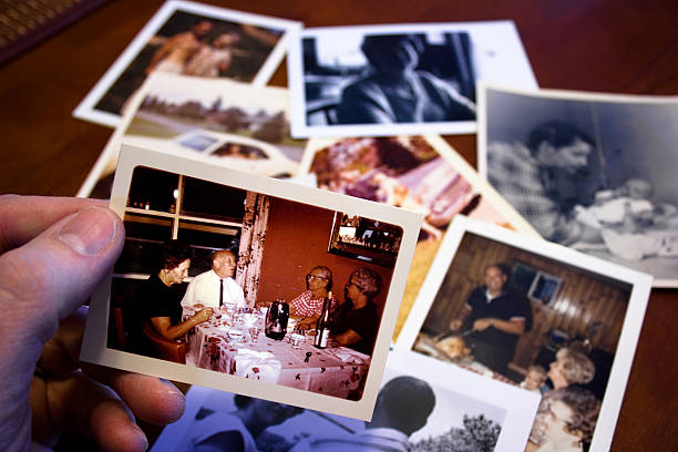 hand holds vintage photograph of parents and grandparent couple - tafel fotos stockfoto's en -beelden