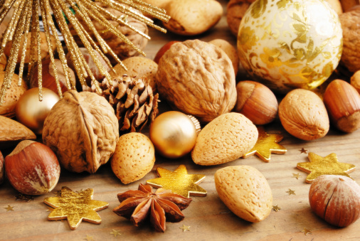 traditional chrismas decoration on wooden background, mixed nuts, golden baubles and golden stars in different seizes