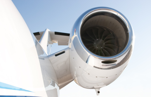 High mounted jet engine of a small business jet with a blue sky in the background. The jet engine is reflected in the fuselage.