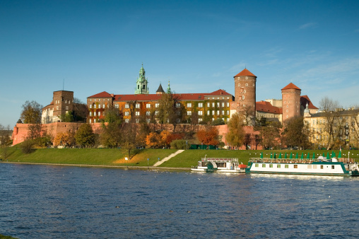 Krakow, Poland - September 19, 2018 - The Wawel Castle and tour boat on Vistula River with tourists on sightseeing tour.