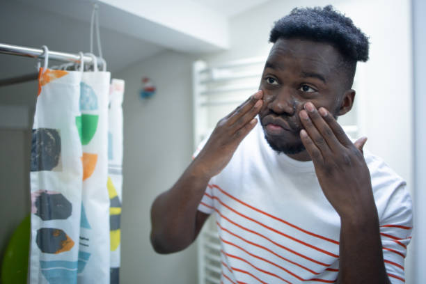 istock Smiling young man applying moisturizer to his face 1575118252