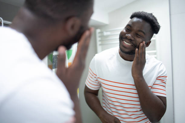 istock Smiling young man applying moisturizer to his face 1575118320