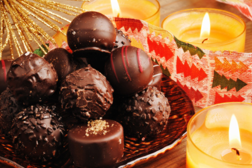 chocolate truffles on a brown plate with chrismas decoration, burning candles and ribbon