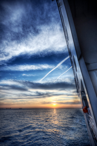 Dramatic sunset seen from the side deck of a large ship.
